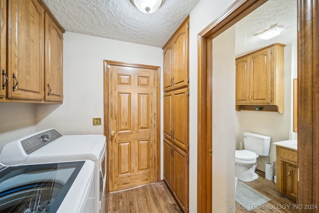 washroom with hardwood / wood-style floors, washer and dryer, cabinets, and a textured ceiling