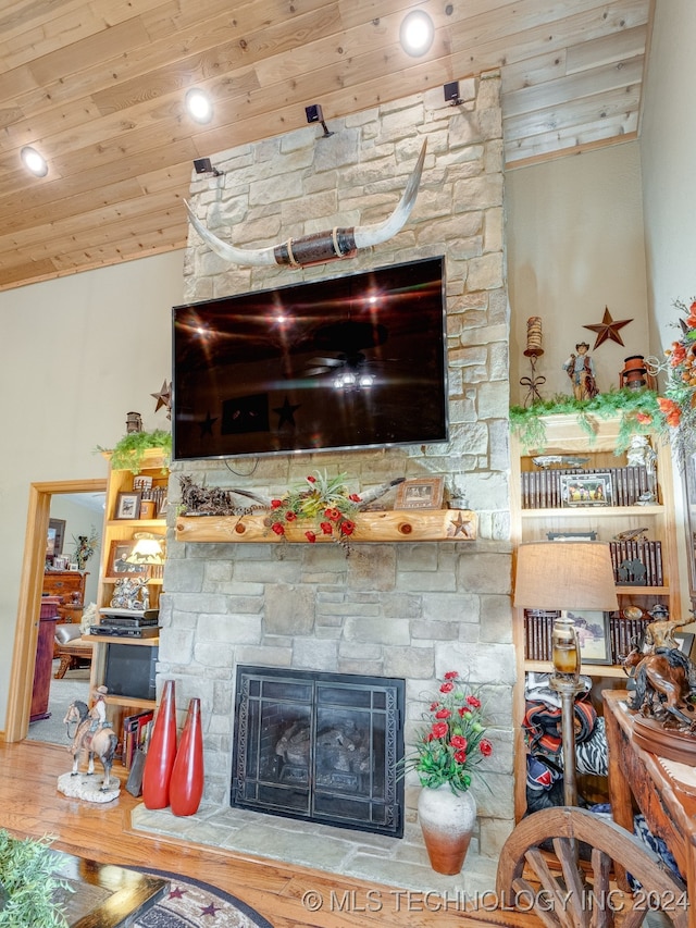 living room with wood-type flooring, lofted ceiling, a stone fireplace, and wooden ceiling