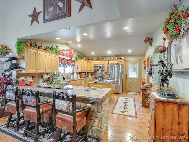 kitchen featuring sink, backsplash, light hardwood / wood-style floors, a kitchen bar, and appliances with stainless steel finishes