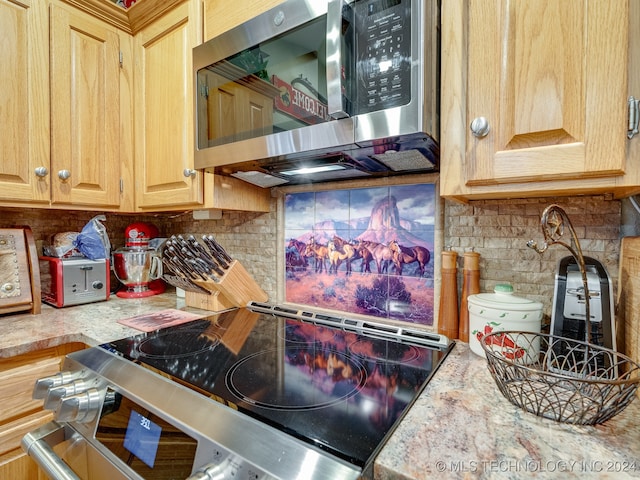 kitchen featuring appliances with stainless steel finishes, backsplash, and light stone counters