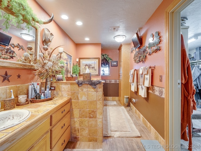 bathroom featuring hardwood / wood-style floors, vanity, and tile walls