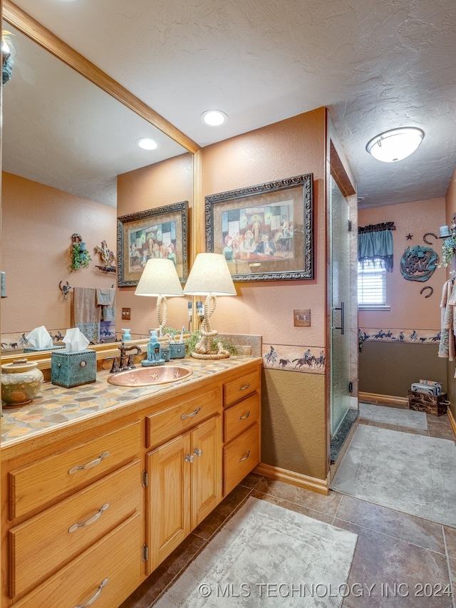 bathroom featuring vanity, a shower with shower door, and a textured ceiling