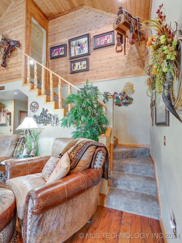 stairway with hardwood / wood-style floors, high vaulted ceiling, wooden ceiling, and wooden walls