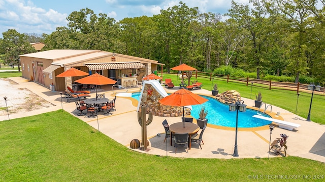 view of swimming pool featuring a patio area, a diving board, a yard, and a water slide