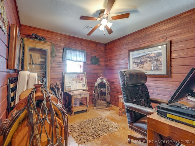 office with a textured ceiling, ceiling fan, and wooden walls