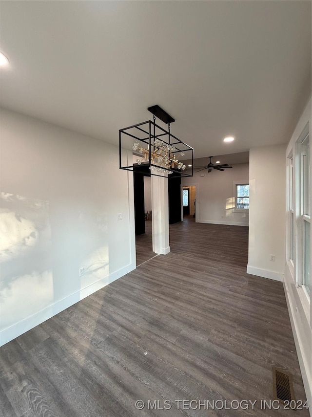 unfurnished dining area with ceiling fan and dark wood-type flooring