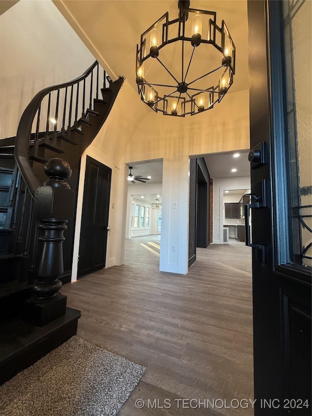 interior space with hardwood / wood-style floors, a towering ceiling, and ceiling fan with notable chandelier