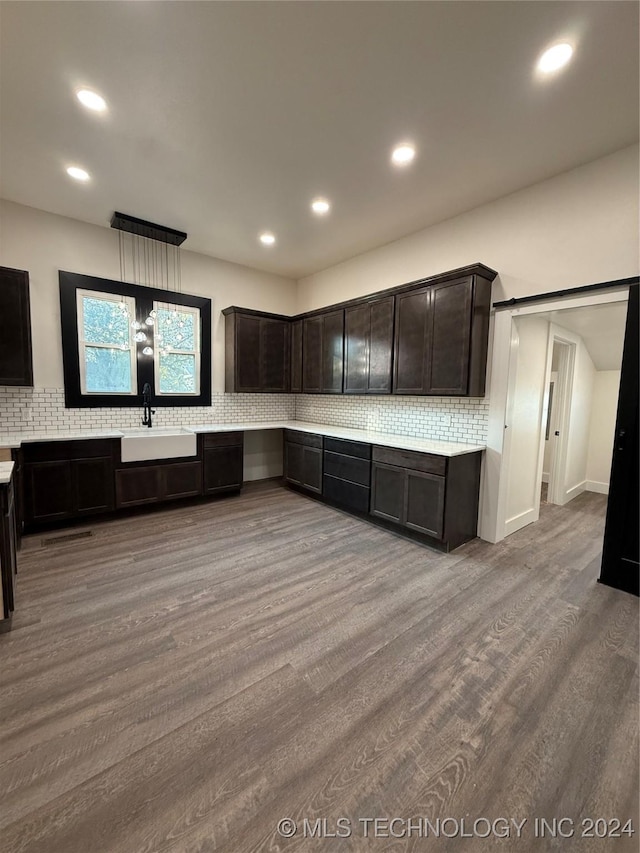 kitchen with tasteful backsplash, dark brown cabinetry, sink, and hardwood / wood-style flooring