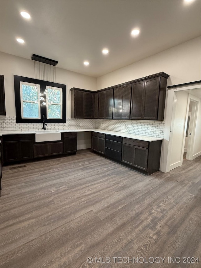 kitchen with dark brown cabinets, light wood-type flooring, sink, and tasteful backsplash