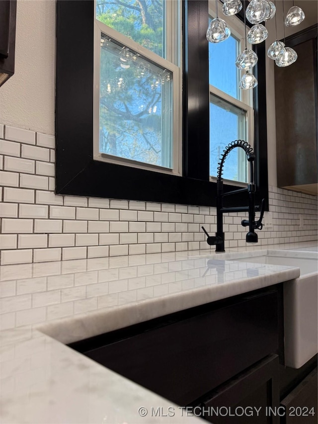 room details featuring decorative backsplash, light stone counters, and hanging light fixtures