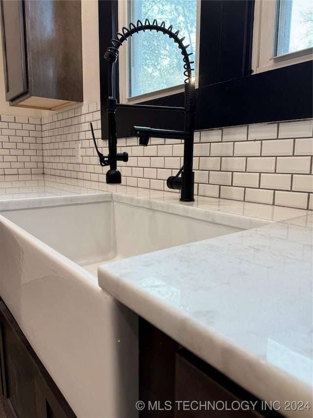 interior details with dark brown cabinetry, light stone countertops, and backsplash