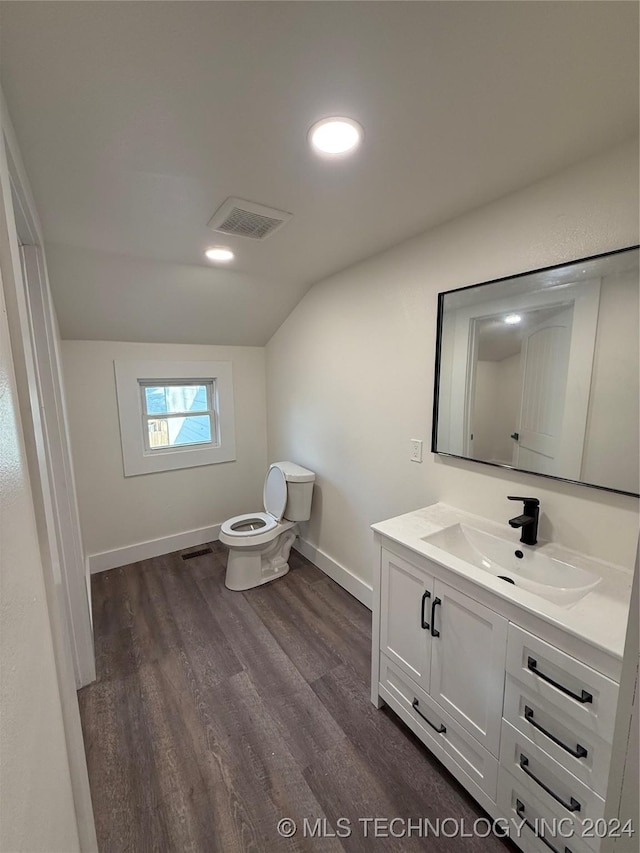 bathroom with vanity, hardwood / wood-style flooring, toilet, and lofted ceiling