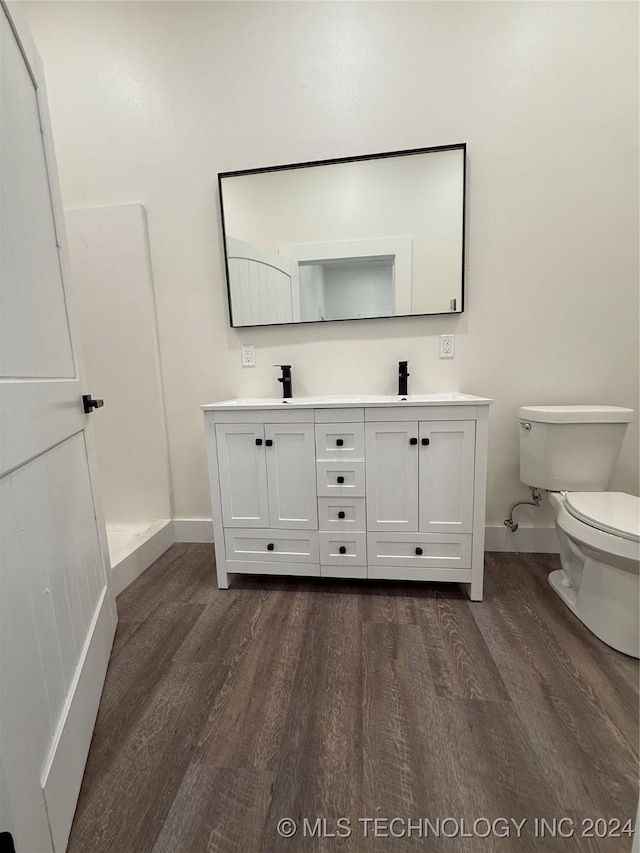 bathroom with a shower, vanity, wood-type flooring, and toilet