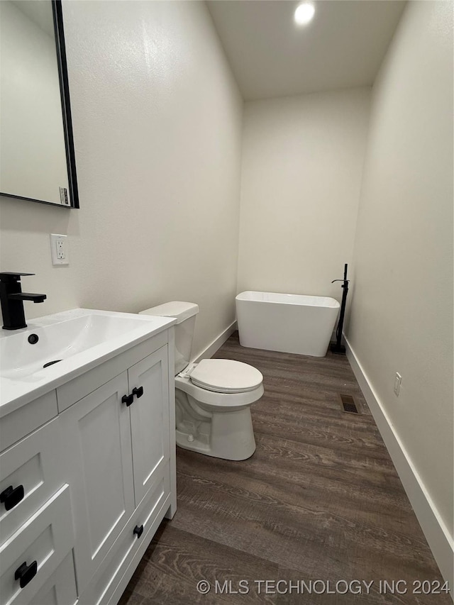 bathroom with a bathtub, hardwood / wood-style floors, vanity, and toilet