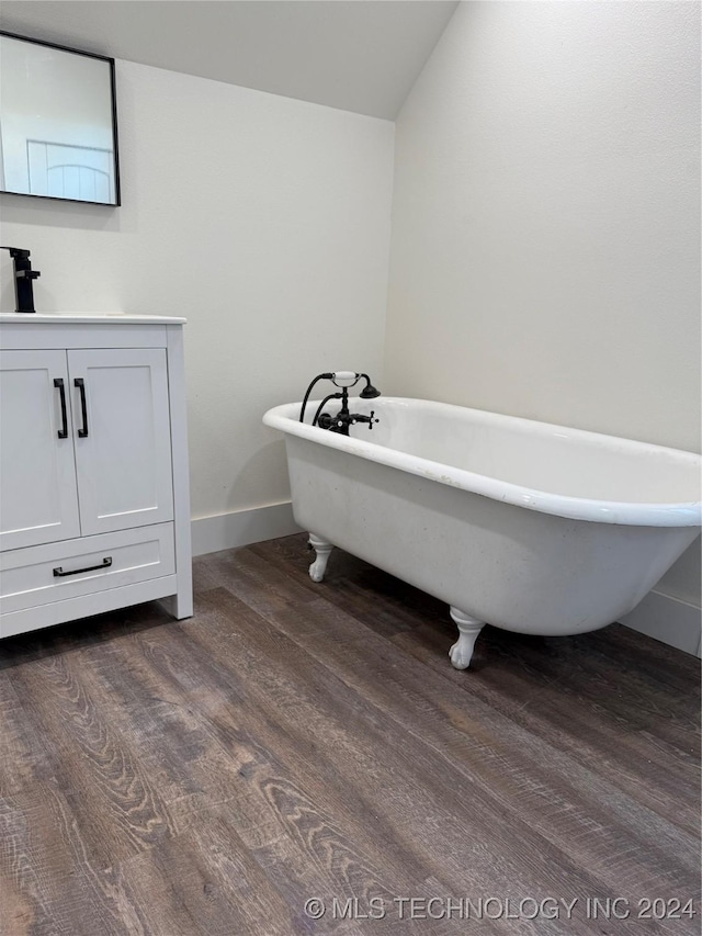 bathroom with a washtub, wood-type flooring, and vanity