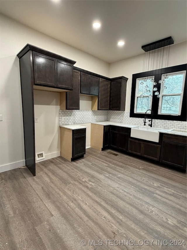 kitchen with tasteful backsplash, dark brown cabinetry, sink, and light wood-type flooring