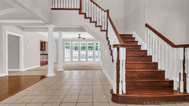 entrance foyer with ornate columns, light tile patterned floors, and a towering ceiling