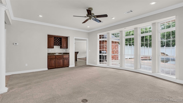 unfurnished living room with light carpet, ornamental molding, and indoor wet bar