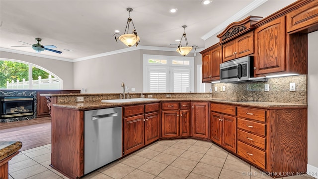 kitchen featuring decorative light fixtures, sink, stainless steel appliances, and crown molding