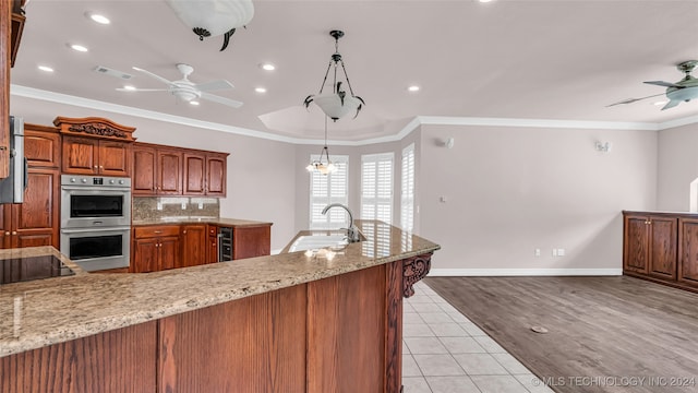 kitchen featuring sink, light hardwood / wood-style flooring, ornamental molding, decorative light fixtures, and stainless steel double oven