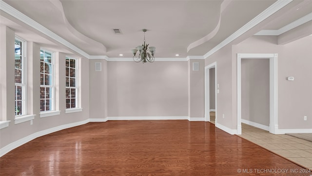 spare room featuring hardwood / wood-style flooring, crown molding, and a notable chandelier