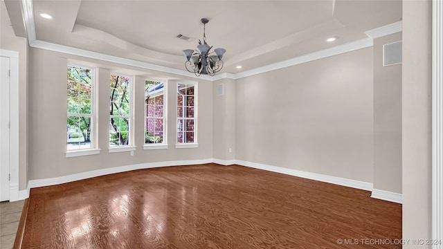 spare room with an inviting chandelier, a raised ceiling, dark wood-type flooring, and crown molding