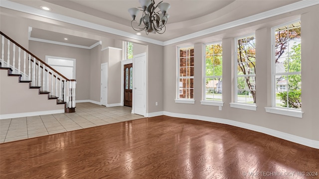 interior space featuring a wealth of natural light, light hardwood / wood-style flooring, crown molding, and a notable chandelier