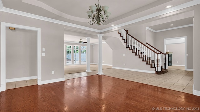 interior space featuring ceiling fan with notable chandelier, wood-type flooring, ornamental molding, and decorative columns