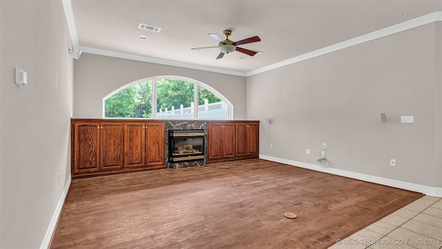 unfurnished living room with ceiling fan, a fireplace, light hardwood / wood-style floors, and ornamental molding