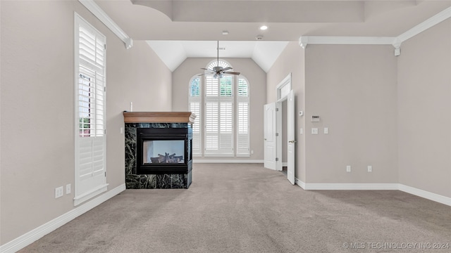 unfurnished living room featuring lofted ceiling, light carpet, a high end fireplace, crown molding, and ceiling fan