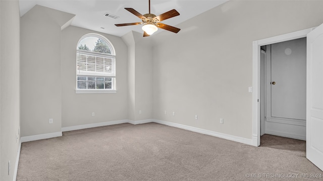 empty room featuring ceiling fan, light colored carpet, and vaulted ceiling