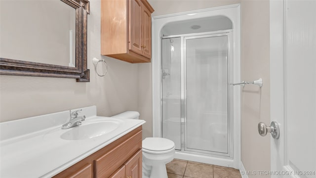 bathroom featuring tile patterned floors, vanity, a shower with shower door, and toilet