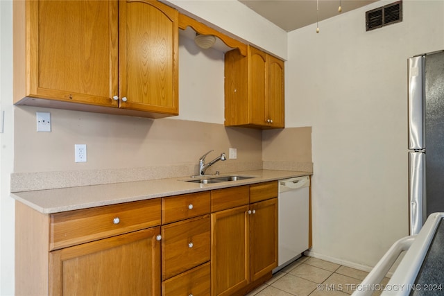 kitchen with stainless steel refrigerator, dishwasher, light tile patterned flooring, and sink