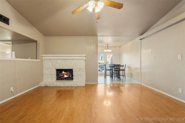 unfurnished living room with a fireplace, wood-type flooring, ceiling fan with notable chandelier, and vaulted ceiling