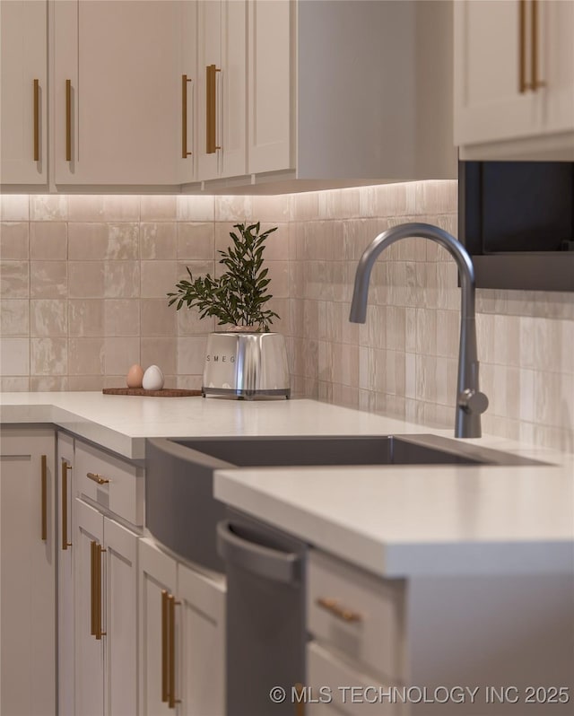 kitchen with white cabinetry, dishwasher, sink, and decorative backsplash