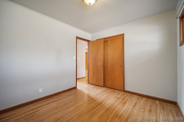 unfurnished bedroom with a closet, ornamental molding, and light wood-type flooring