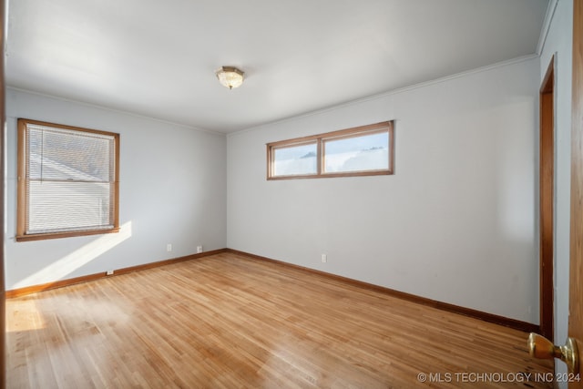 spare room featuring crown molding and light hardwood / wood-style flooring