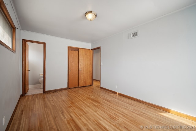 unfurnished bedroom with light wood-type flooring, ensuite bathroom, and crown molding