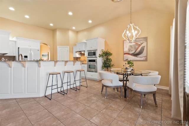 tiled dining room featuring high vaulted ceiling and a chandelier