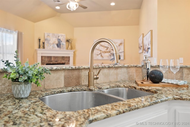 kitchen with decorative backsplash, lofted ceiling, sink, and a brick fireplace