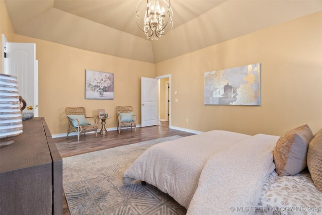 bedroom with hardwood / wood-style floors, a notable chandelier, and vaulted ceiling