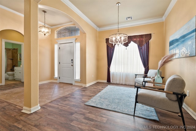 foyer entrance featuring hardwood / wood-style flooring, crown molding, and a notable chandelier