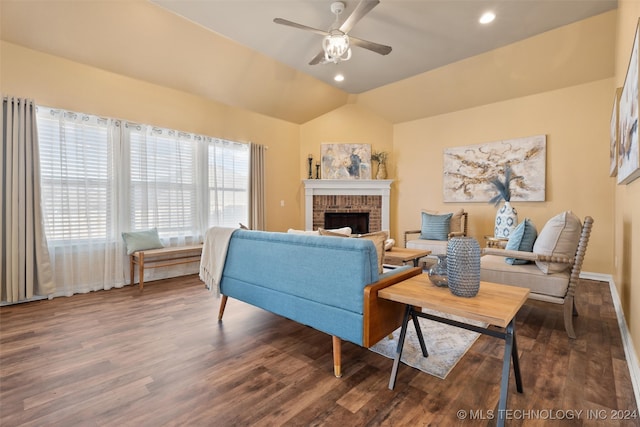 living room with ceiling fan, dark hardwood / wood-style floors, lofted ceiling, and a brick fireplace