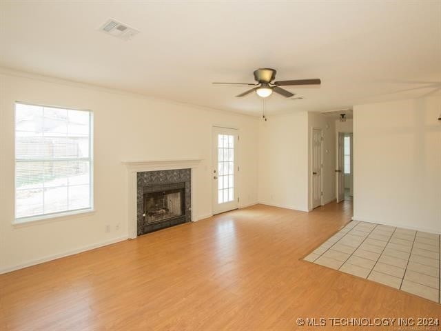 unfurnished living room featuring ceiling fan, a premium fireplace, and light hardwood / wood-style flooring