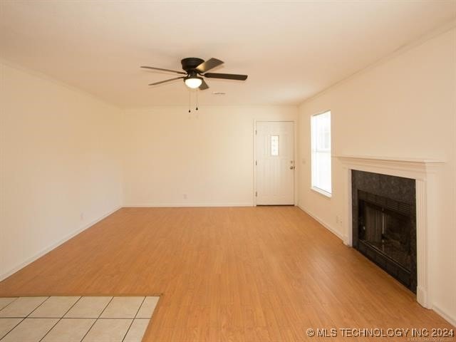 1132 W Florence Ct, Broken Arrow, OK 74011 - unfurnished living room featuring a ceiling fan, light wood finished floors, a tile fireplace, and baseboards