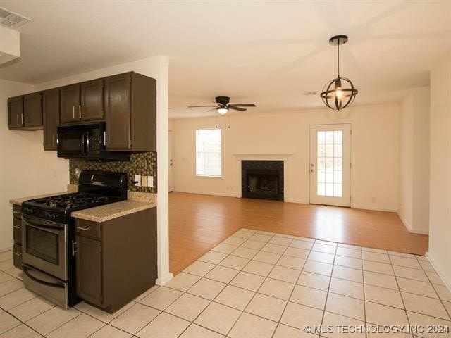 1132 W Florence Ct, Broken Arrow, OK 74011 - kitchen featuring stainless steel range with gas stovetop, black microwave, a fireplace, ceiling fan, and light countertops