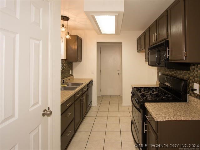 kitchen with dark brown cabinetry, sink, light tile patterned floors, and black appliances