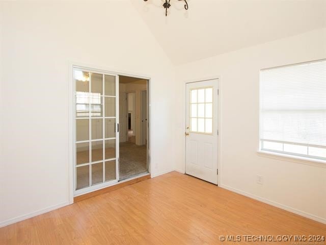 spare room with lofted ceiling and light wood-type flooring