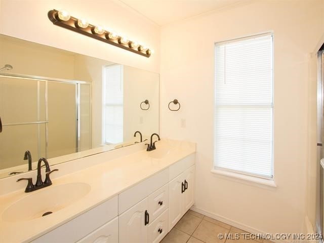 bathroom with tile patterned floors, plenty of natural light, an enclosed shower, and vanity