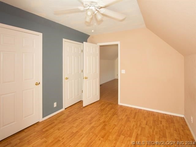 unfurnished bedroom with ceiling fan, light wood-type flooring, and lofted ceiling